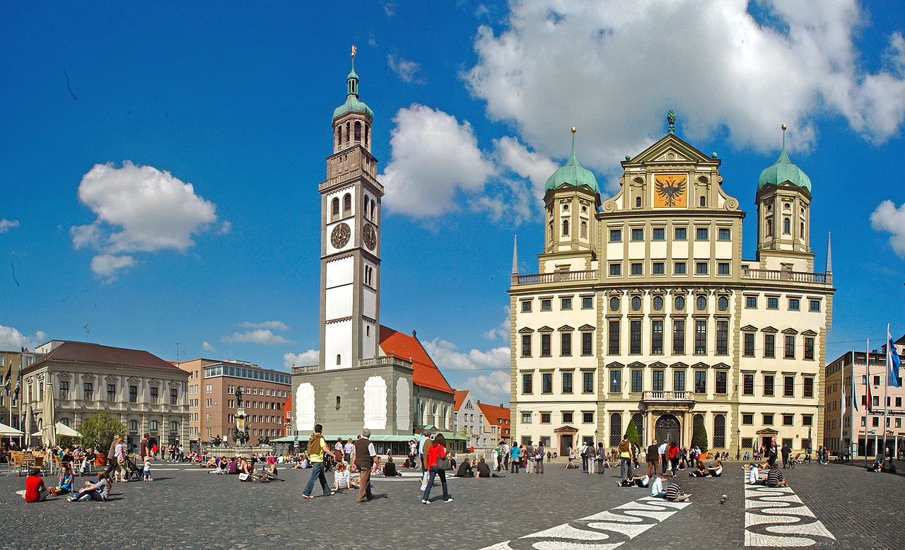 Augsburg ist eine Stadt mit gepflasterten Straßen, Kirchen und hohen Türmen