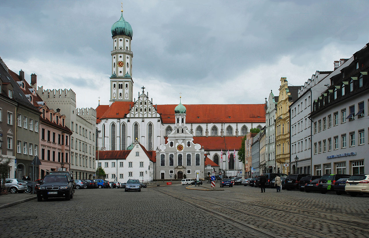 Augsburg ist eine Stadt mit gepflasterten Straßen, Kirchen und hohen Türmen